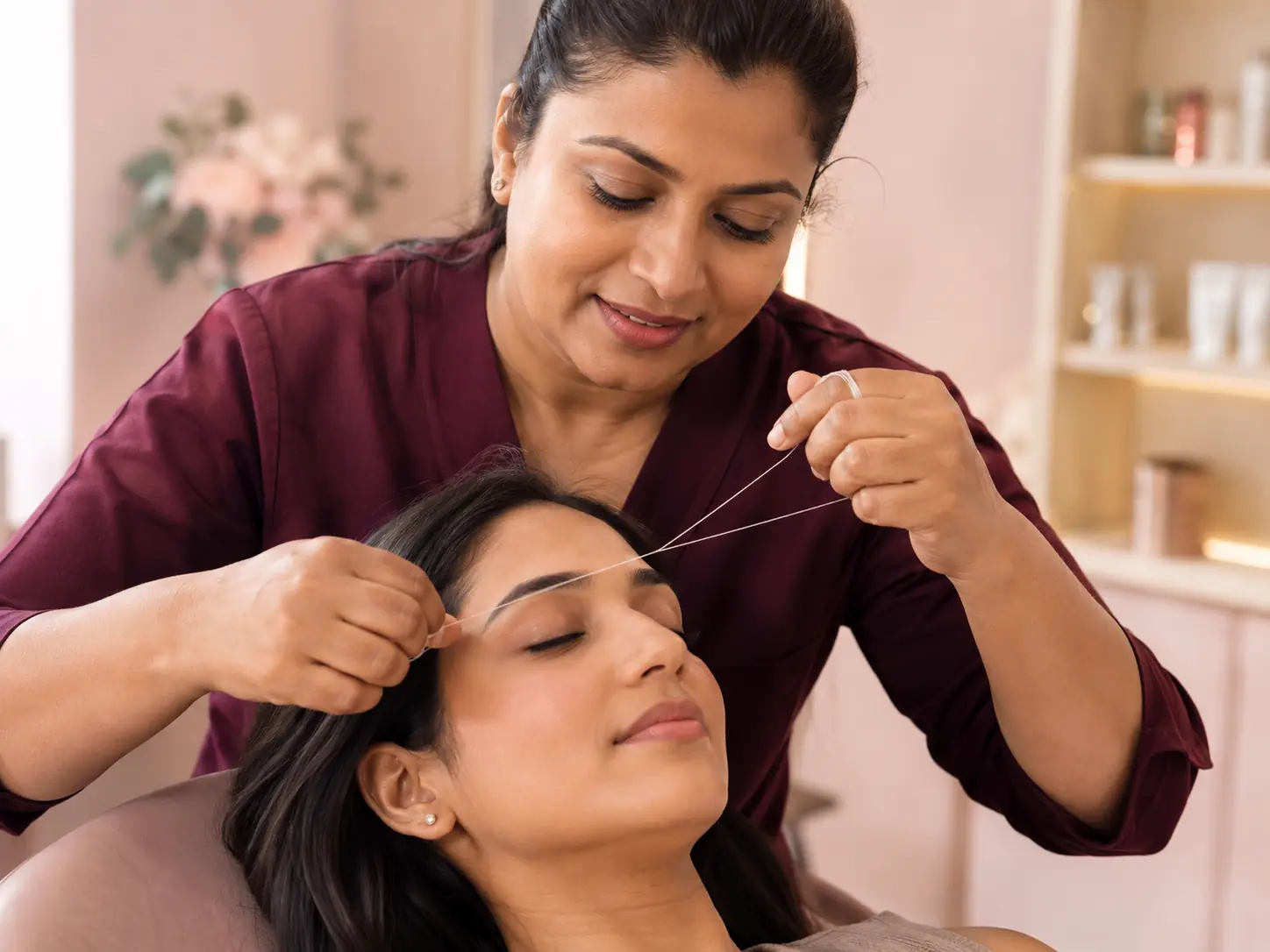 A Myra Eyebrows stylist shaping a client's eyebrows with threading.